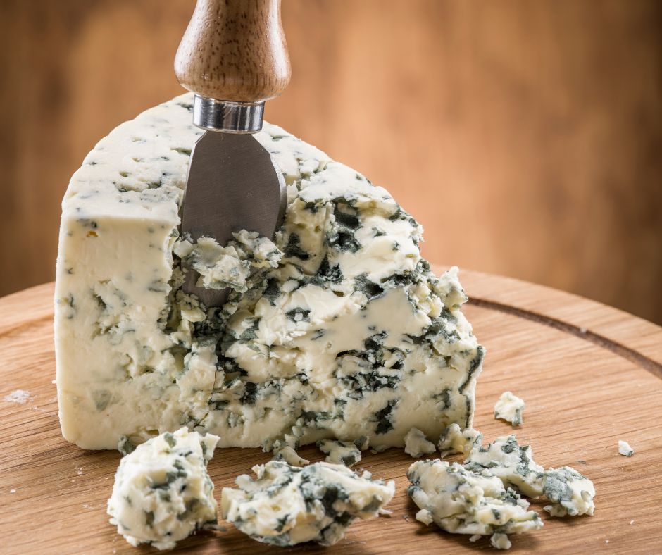 Portion de fromage bleu sur un plateau en bois avec un couteau à fromages